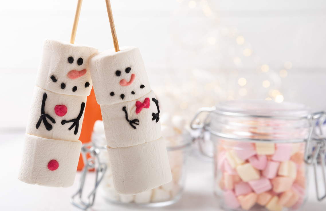 Hot chocolate mug with melted marshmallow snowman.Sweet treat for kids funny marshmallow snowman. Christmas winter holiday decoration. New Year card.Winter hot drink.